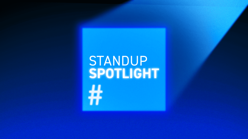 Bright blue square with the words 'STANDUP SPOTLIGHT' and a hashtag symbol, illuminated by a spotlight.